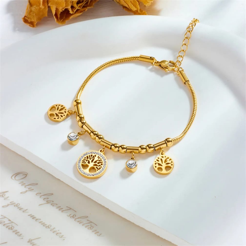 Gold bracelet with tree of life charms on a white surface