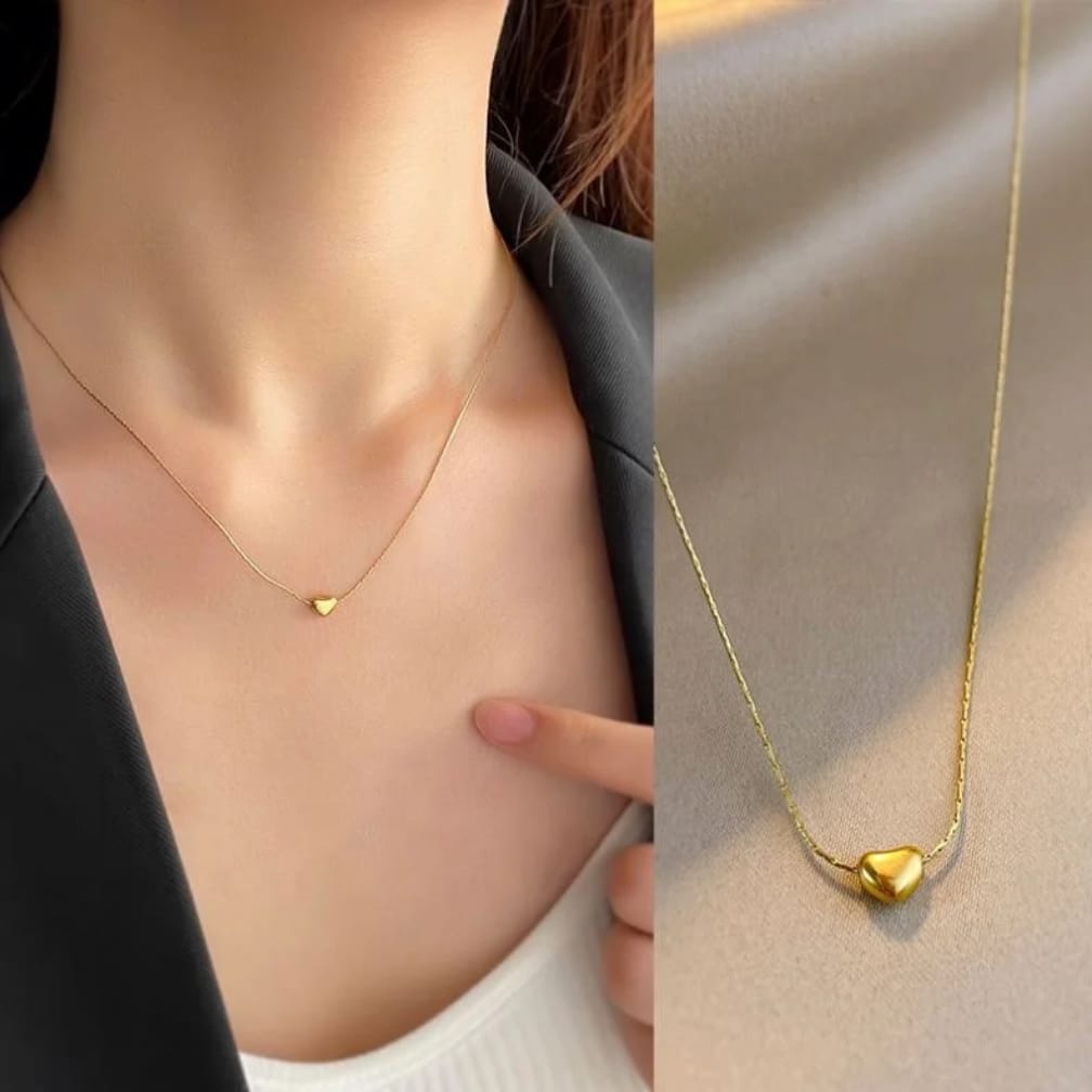 Gold heart-shaped necklace on a person's neck with close-up of pendant.