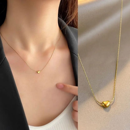 Gold heart-shaped necklace on a person's neck with close-up of pendant.