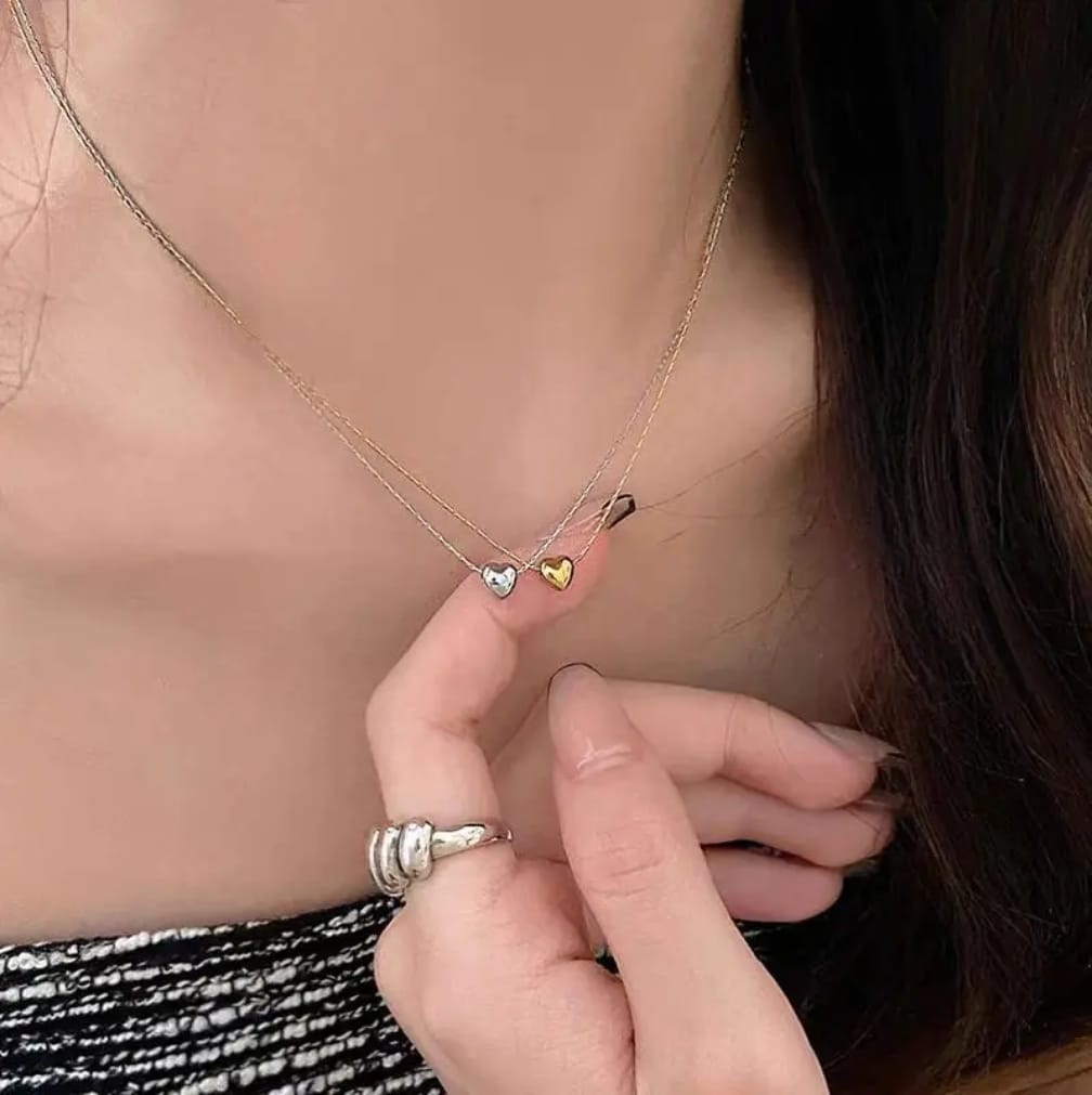 Close-up of a person wearing three heart-shaped pendants on a necklace.