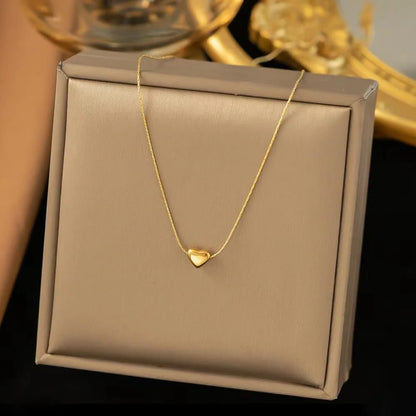 Gold necklace with a heart pendant on a beige jewelry box