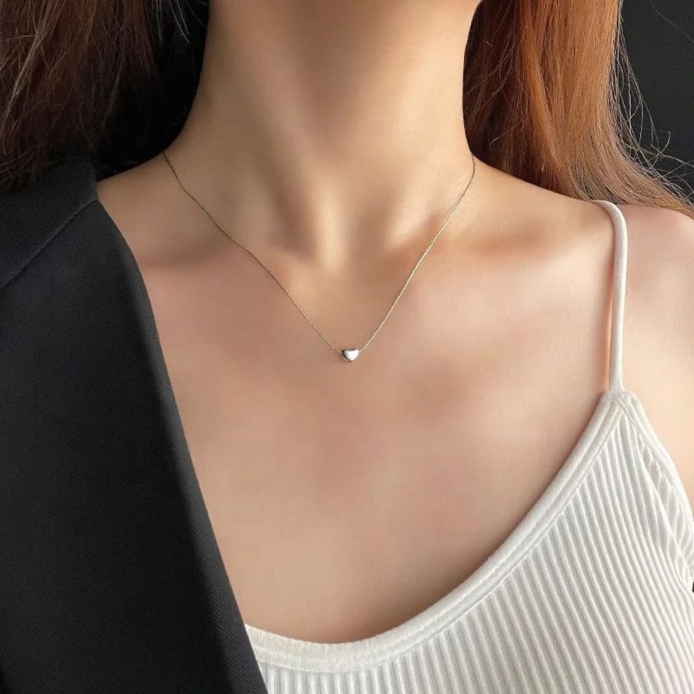 Woman wearing a delicate necklace with a heart pendant